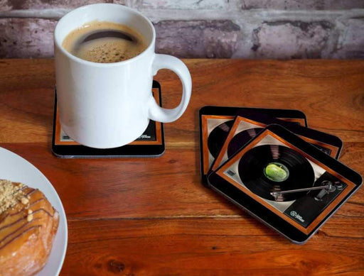 four coasters on a table each with image of a vinyl record playing on a record player, with a coffee cup on one coaster and a donut in the back ground