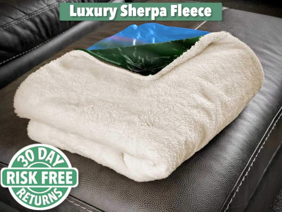 A sherpa fleece blanked folded up and sat on a couch
