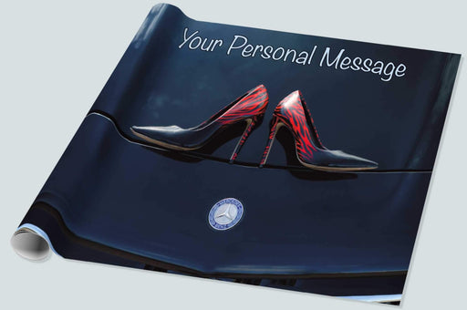 A roll of wrapping paper showing a pair of shoes on the bonnet or hood of a dark purple car, the logo of the car being visible below the shoes, the image is seen from above, and there is a personal message