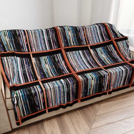 A blanket draped over a couch, the blanket having an image of a vinyl record collection on it