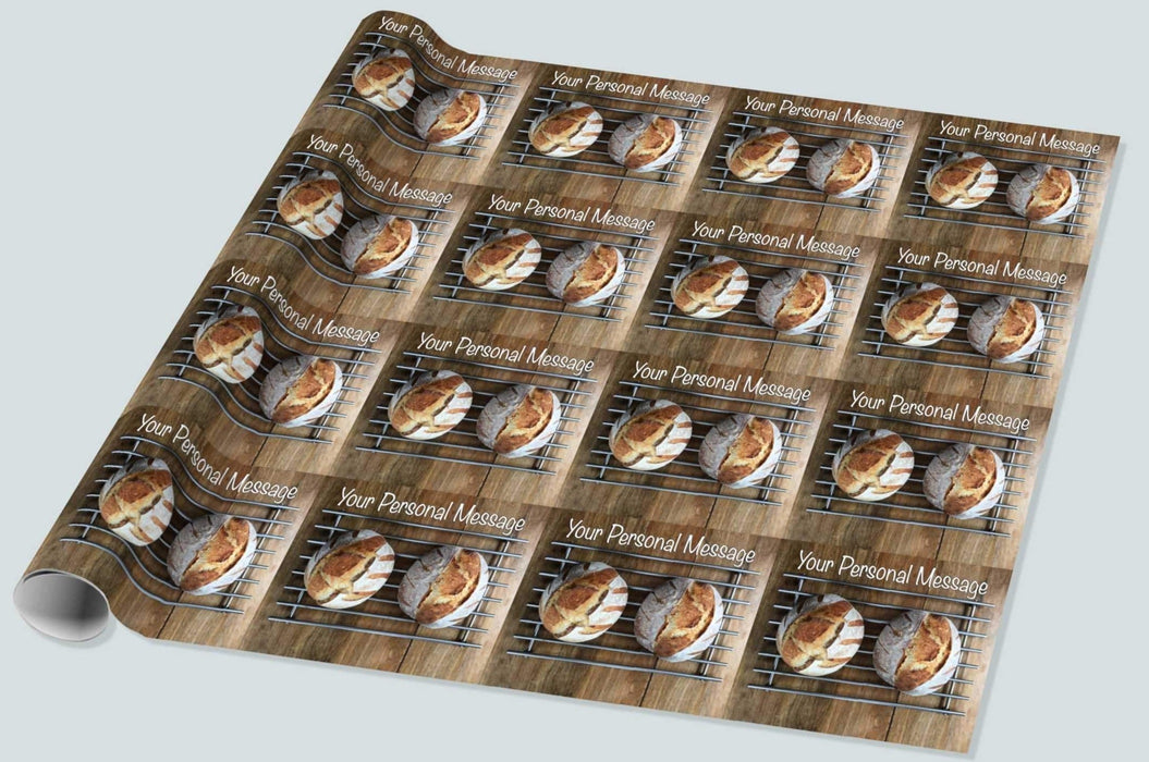 A roll of wrapping paper showing a pair of sourdough loaves resting on a metal tray upon a brown wooden table, along with a personal message, the image repeated in a mosaic pattern