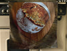image of an apron hung next to a kitchen cooker, the apron has an image of a sourdough loaf of bread on it