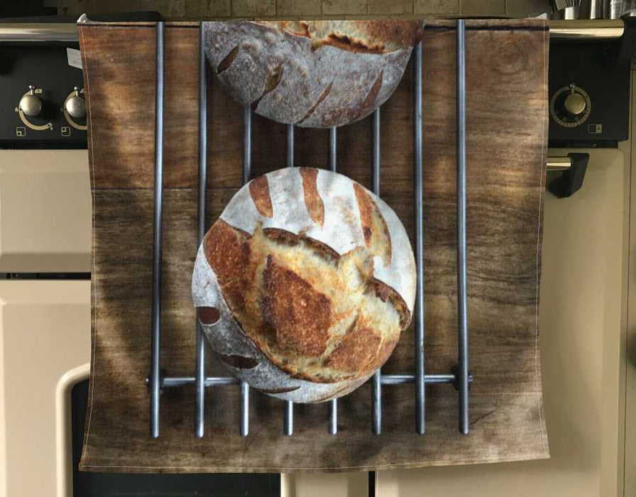 An apron hung over a cooker, the apron having an image of a pair of sour dough loaves on it