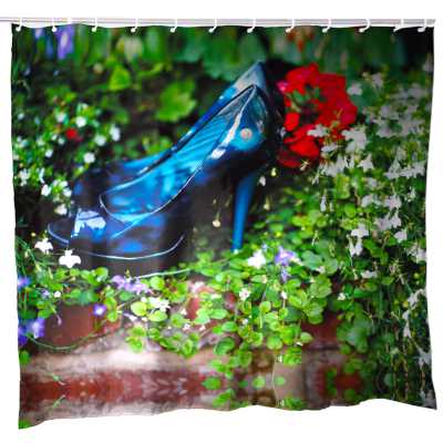 A shower curtain, the curtain having an image of a pair of blue high heel shoes resting in a bed of flowers and green leaves.