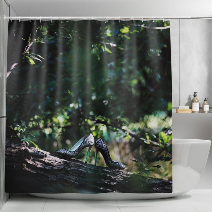 a shower curtain in a bathroom, the curtain showing a pair of high heel shoes resting on a branch of a tree within a forest