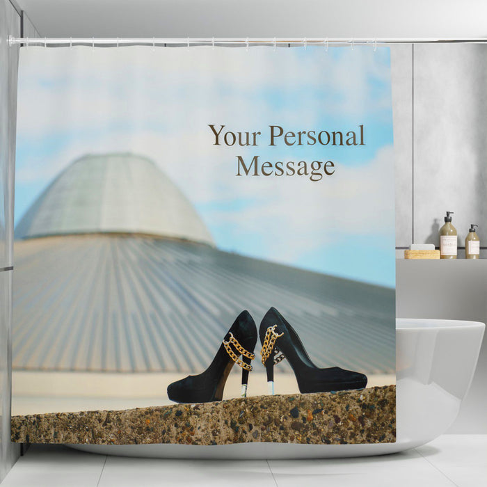 A shower curtain in a bathroom, the shower curtain having an image of a pair of black high heel shoes on a wall in the foreground, with a building and city skyline in the background