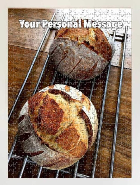 A jigsaw showing an image of two sourdoughs loaves siting on a wire tray along with a personalised message on the jigsaw