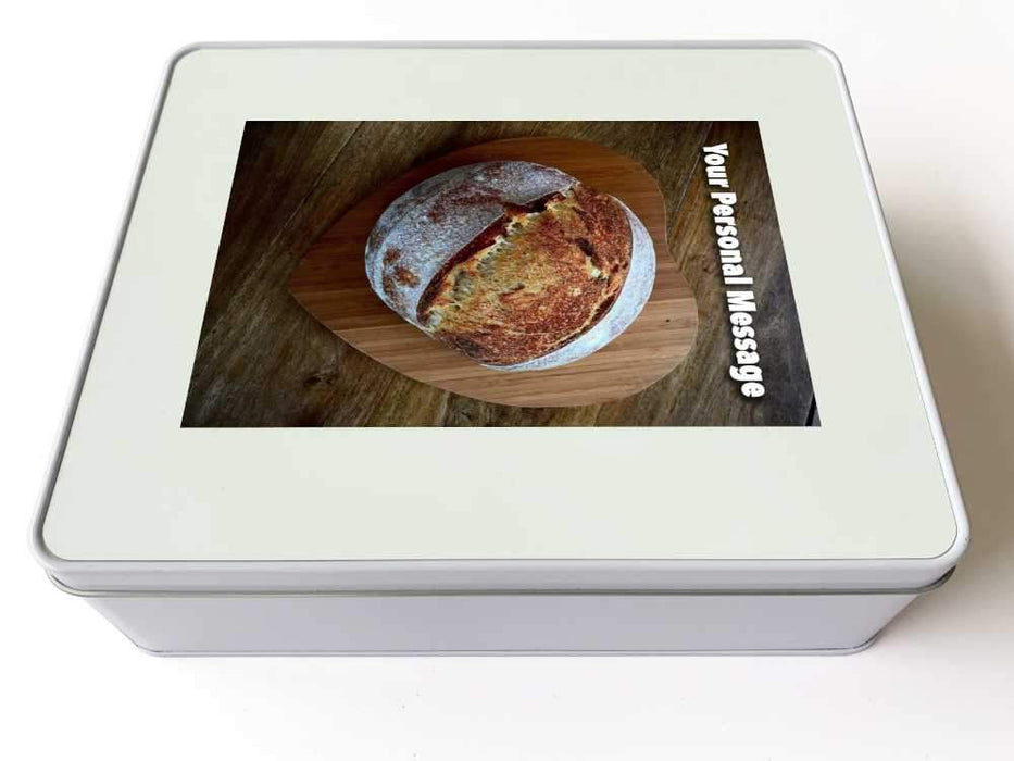 A white tin box with image of top of a sourdougn loaf of bread on top of a heart shaped tray, along with a personal message