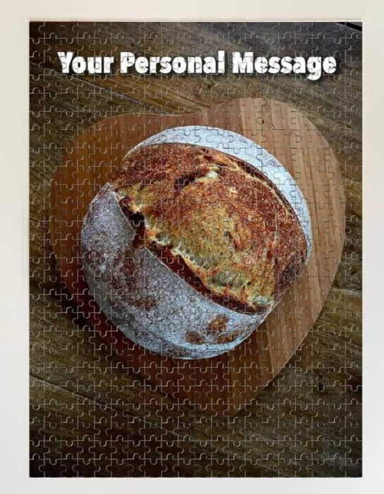 A jigsaw featuring a sourdougn loaf of bread on top of a heart shaped tray, along with a personal message