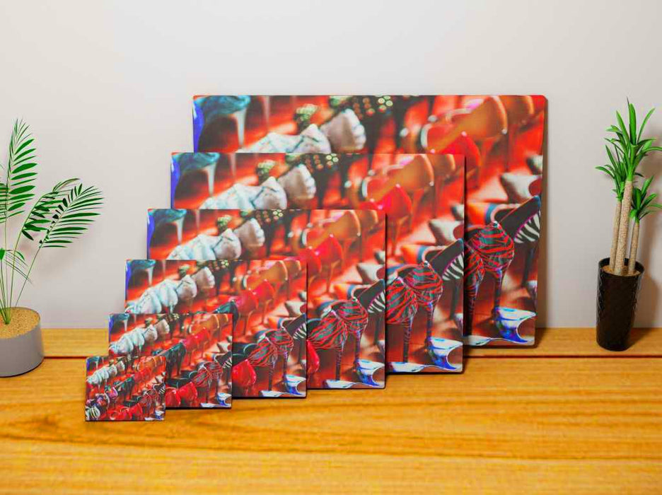 multiple canvas prints of different sizes all laid against each other on a wooden floor, each print showing multiple rows of ladies high heel shoes