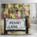 A shower curtain in a bathroom, the curtain having an image of the penny lane road sign in liverpool, upon the sign are four coloured high heel shoes