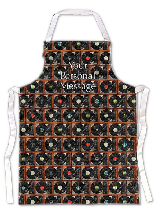 An apron lying on a grey tiled floor, the apron having images of lots of record players with vinyl records in a mosaic pattern and a personal message printed