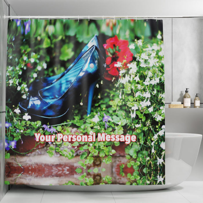 A shower curtain with an image of a pair of blue high heel shoes sat in a flower bed with white and green flowers with a personal message printed