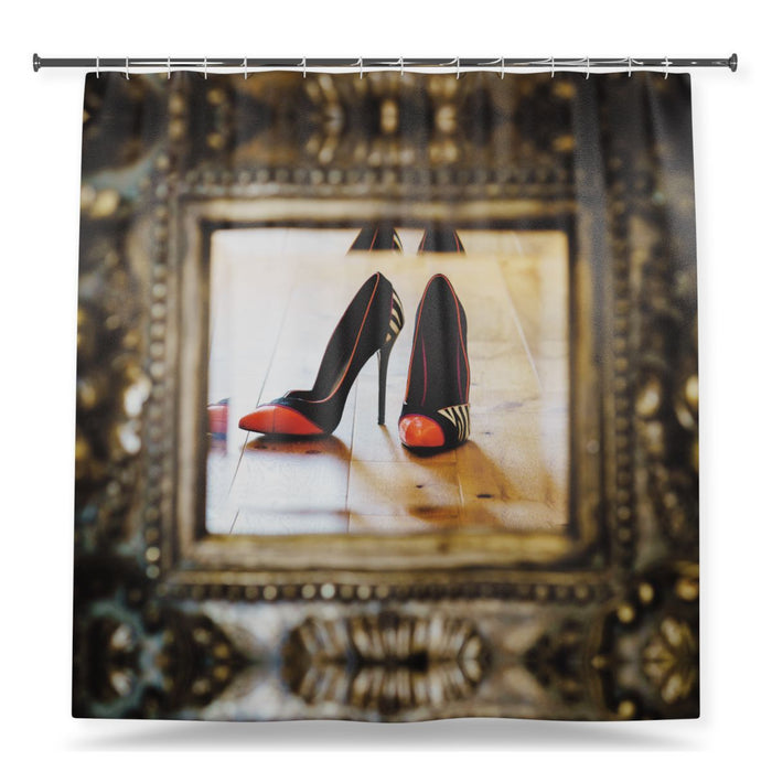 A shower curtain showing an image of a pair of high heel shoes seen in the reflection of a brass mirror, with a white background
