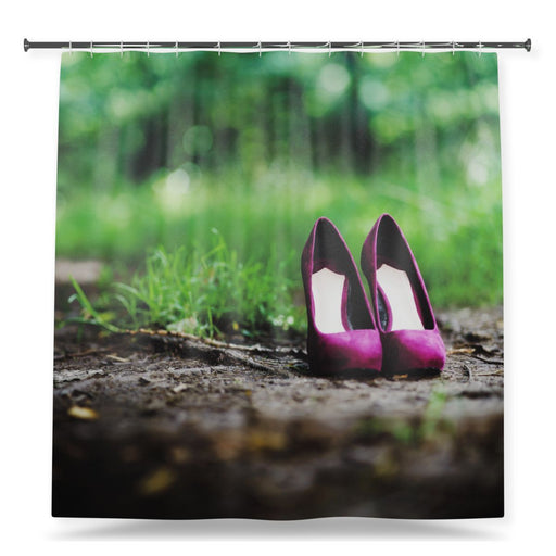 A shower curtain showing an image of a pair of purple high heel shoes stood on a woodland path in a forest, with a white background