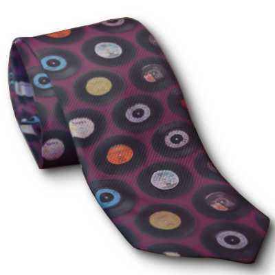 A rolled up neck tie, the tie is burgundy in colour and has a mosaic of vinyl records on it