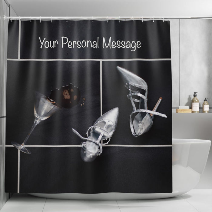 A shower curtain in a bathroom, the shower curtain having an image of a pair of silver high heel shoes on a tiled floor, there is a spilt cocktail next to the shoes, along with a printed personal message on the curtain