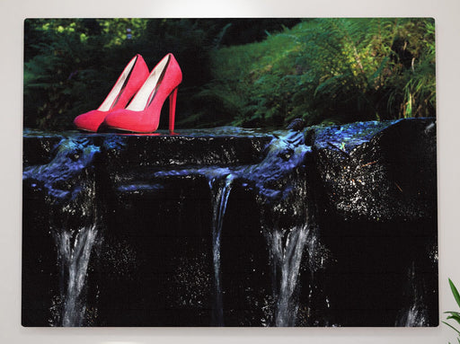 a canvas print hung above a couch, the canvas being an image of a pink pair of shoes on a rock in a flowing river