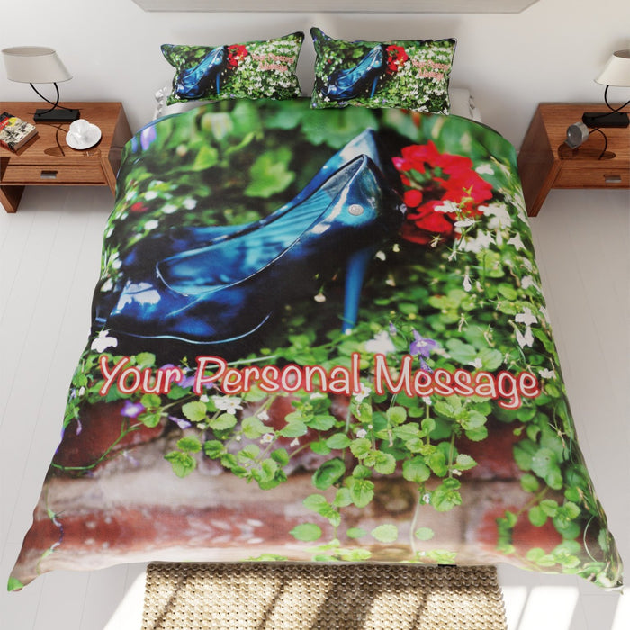 A bed with a duvet cover, the duvet having an image of a pair of blue high heel shoes surrounded by flowers with a personal message printed