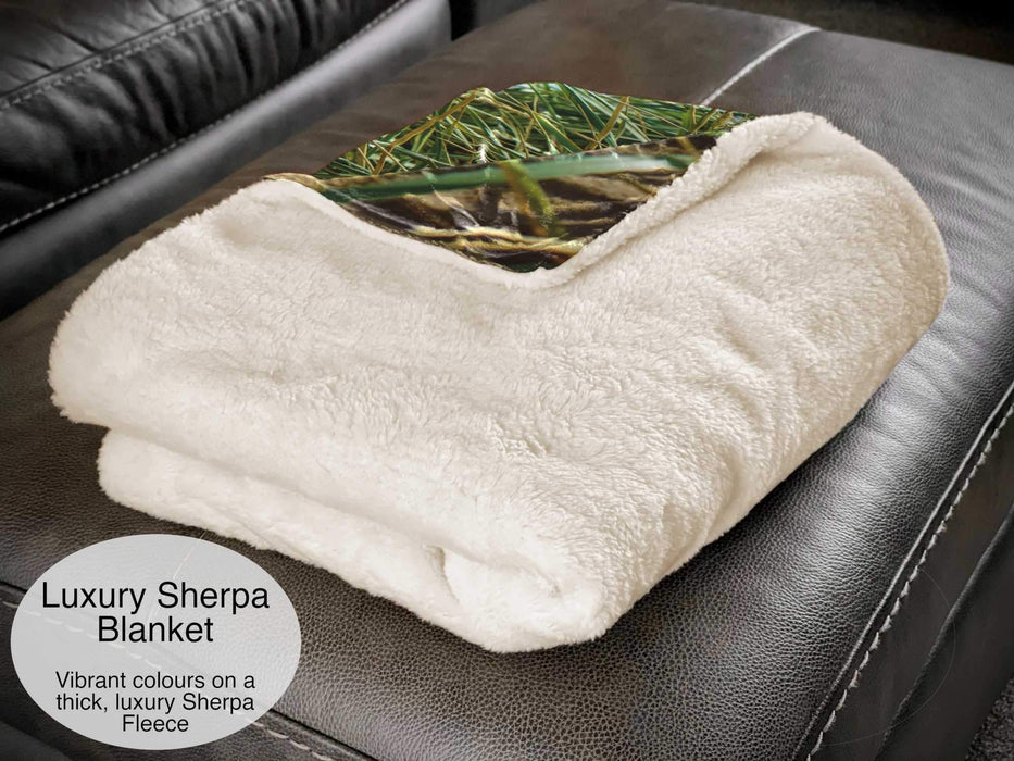A white sherpa blanket folded and sat on a couch