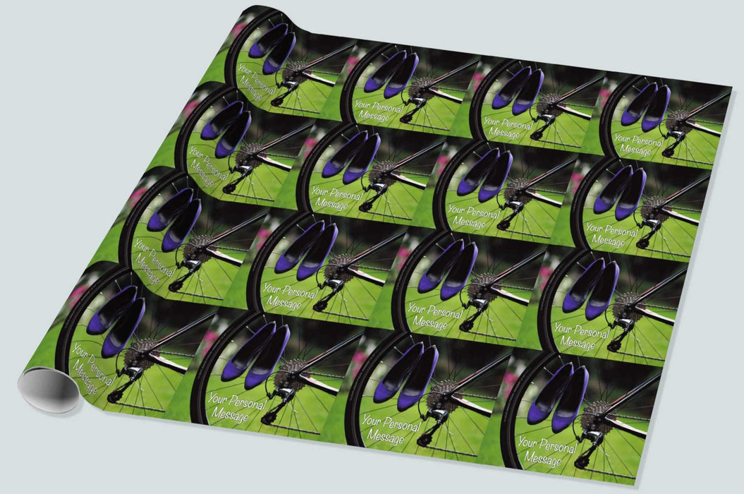 A roll of wrapping paper showing the rear wheel of a racing bicycle with a pair of purple heels hung from the spokes of the wheel, there is grass and trees in the background, and a personal message, the image repeats