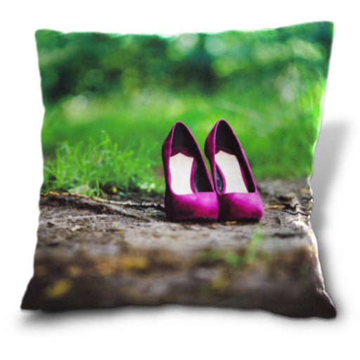 A cushion with an image of a pair of pruple high heels on a path through some woods