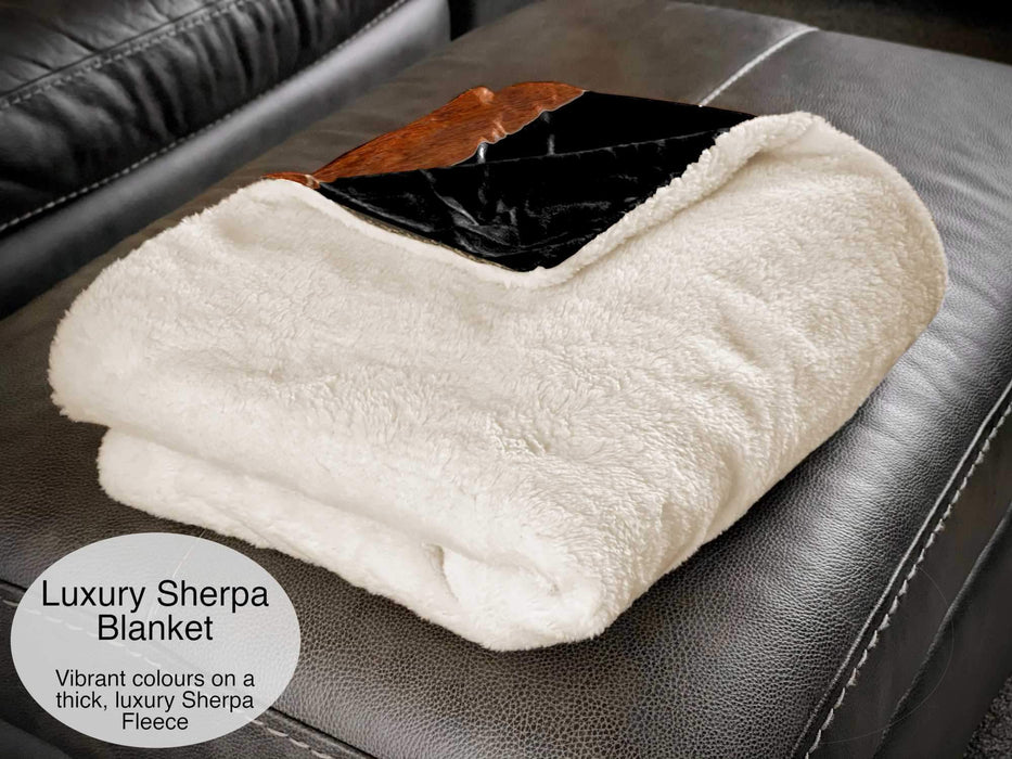 A folded sherpa fleece blanket, mostly showing the white fleece underside, with a folded corner revealing part of an image of a record player