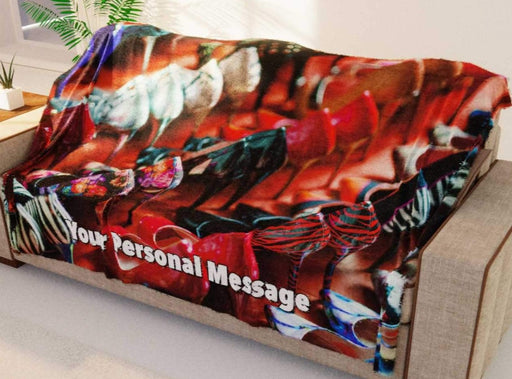 A blanket with an image of lots of high heel shoes in multiple rows, along with a personal message, the blanket being draped over a couch in a living room