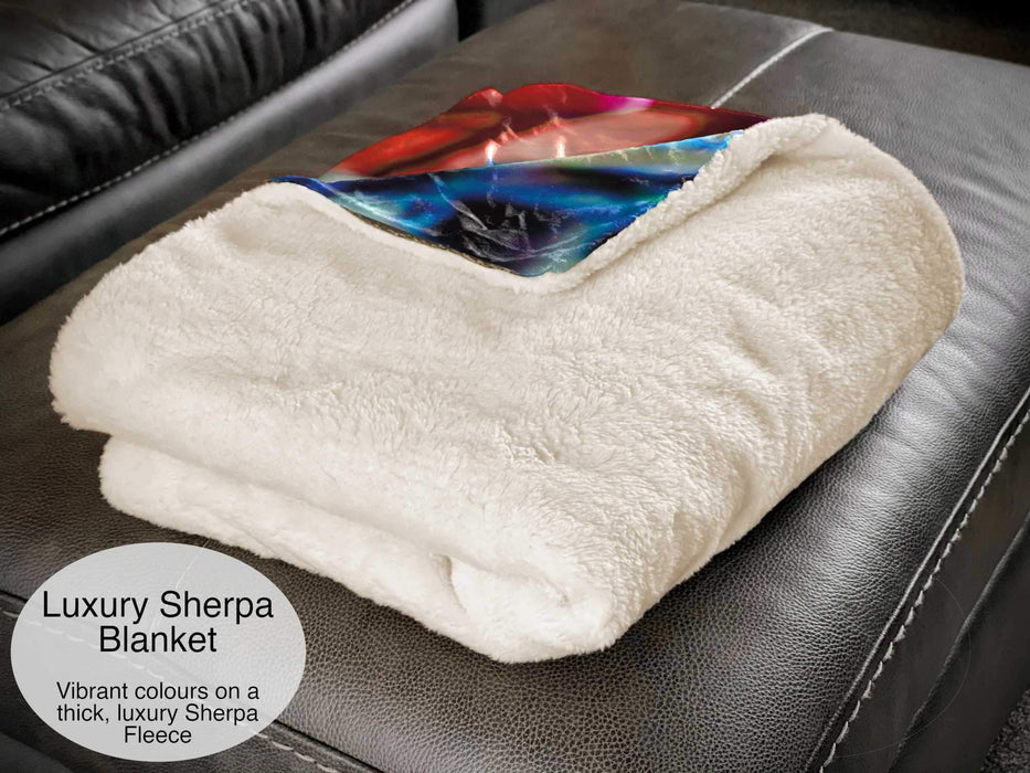 A white sherpa blanket folded and on a couch