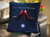 An image of a cushion on a couch, the cushion having an image of a pair of red and blue high heel shoes sat upon the bonet of a car, along with a personalised message