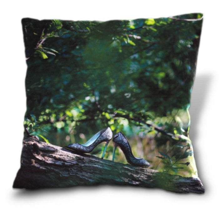 An image of a cushion, the cushion cover shows a pair of shoes sat on a tree branch within a forest woodland