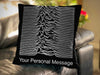 A cushion upon a couch, the cushion being black and having an image of a radio signal as seen on joy divisoins unknown pleasures record cover