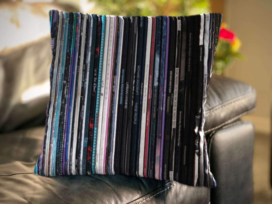 a cushion on a sofa, the cushion having an image of multiple vinyl records stacked along a shelf