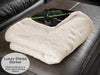 a white fleece blanket folded, with a corner folded towards the viewer showing green and black under the blanket