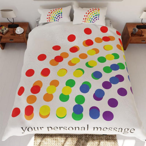 A duvet cover with polka dots on it, the polka dots are coloured using rainbow colours, there is also a personal message printed on the duvet