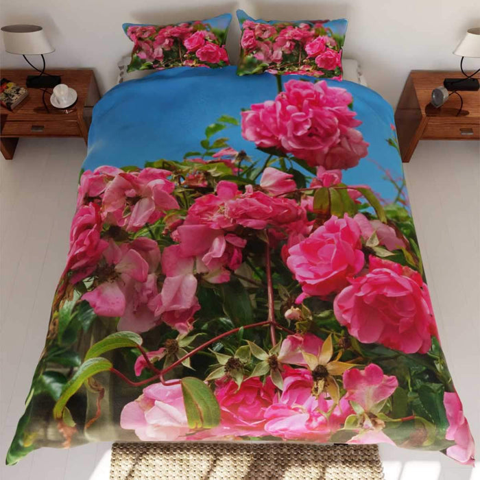 A duvet on a bed, the duvet having a pattern of pink roses with green leaves in the background