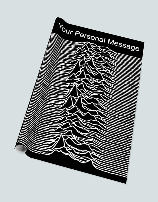 a roll of gift paper on a white background, the gift paper showing a large image of joy divisions famous unknown pleasues pulsar image along with a personal message