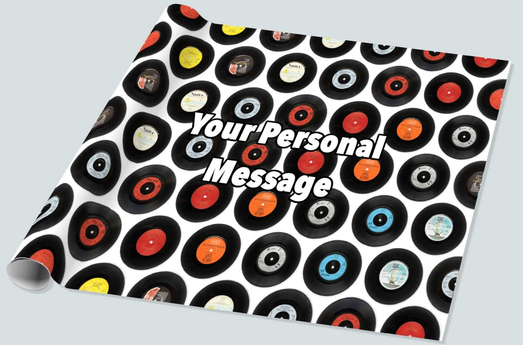a roll of gift wrapping paper on a white background, the gift wrap showing a montage of vinyl records along with a personal message