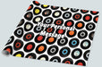 a roll of gift wrapping paper on a white background, the gift wrap showing a montage of vinyl records along with a personal message