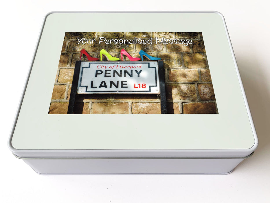 A white tin box, and there is an image on the box of the penny lane road sign along with four high heel shoes sitting on the sign