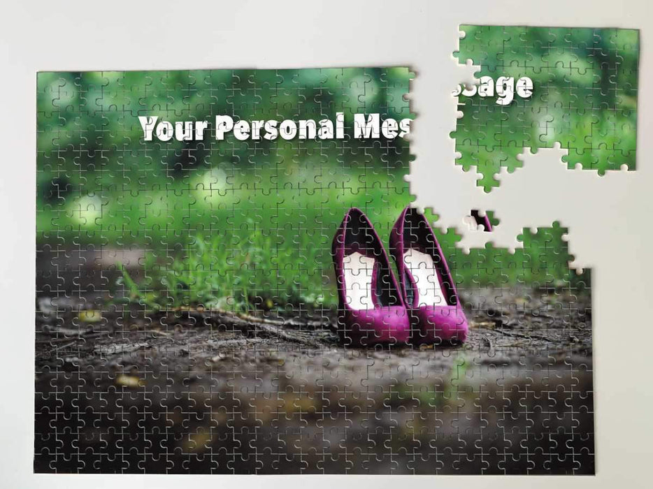 A jigsaw seen from the top, the jigsaw having an image of a pair of purple shoes sitting on a woodland path along with a personal message, the jigsaw is broken into several pieces