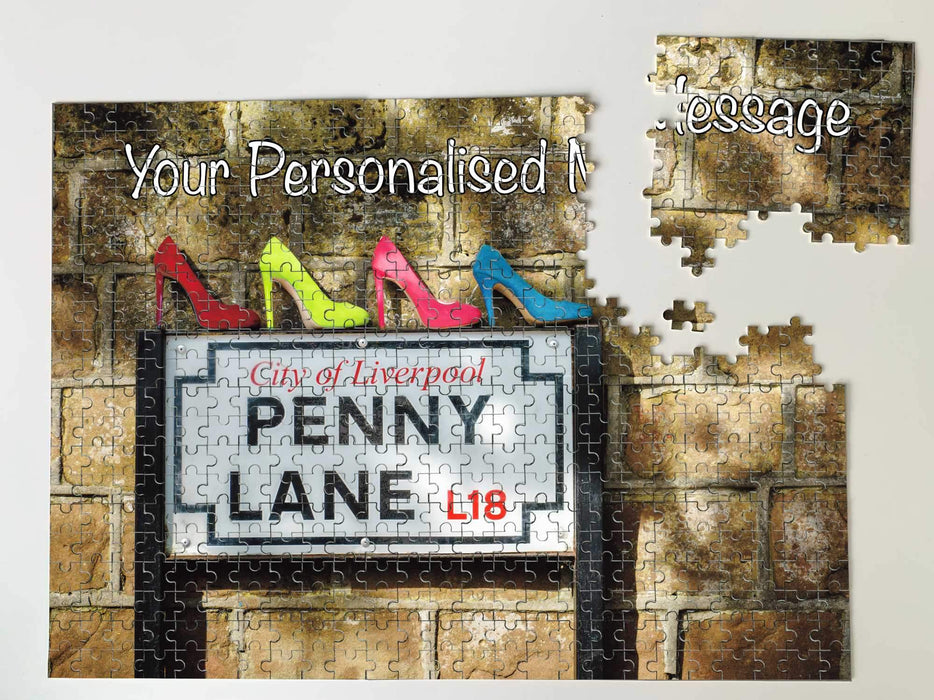 A jigsaw seen from the top, the jigsaw having an image of the famous penny lane road sign with four coloured shoes sat upon the road sign, along with a personal message, the jigsaw is broken into a few pieces
