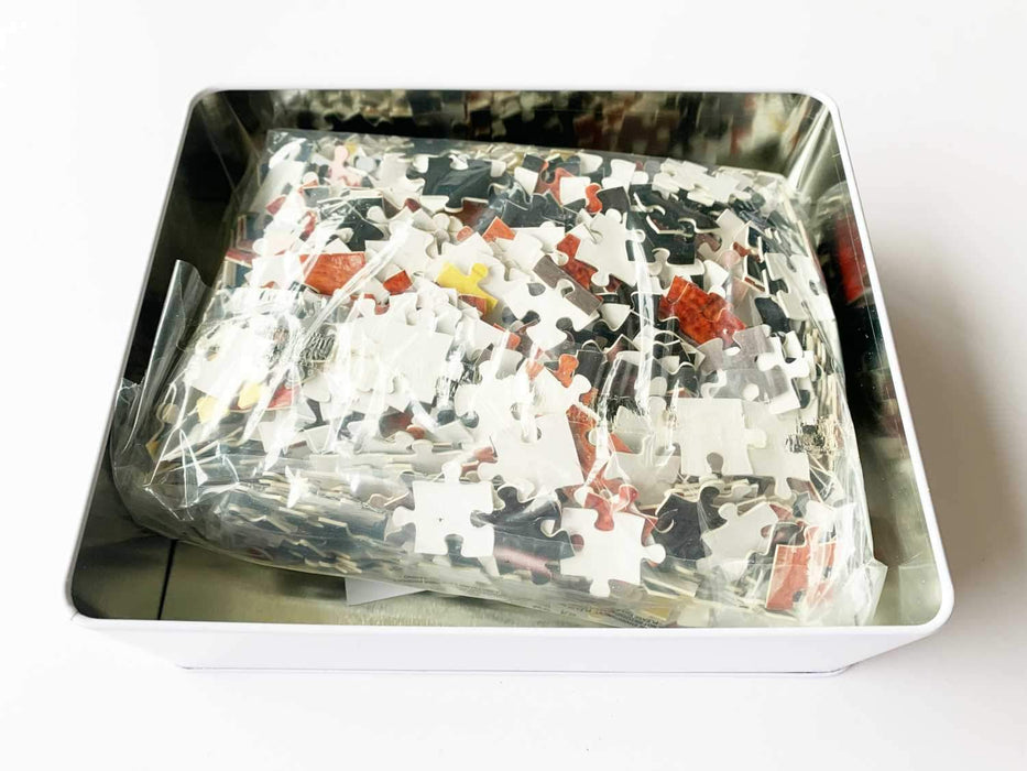 An open tin containing a bag full of jigsaw pieces