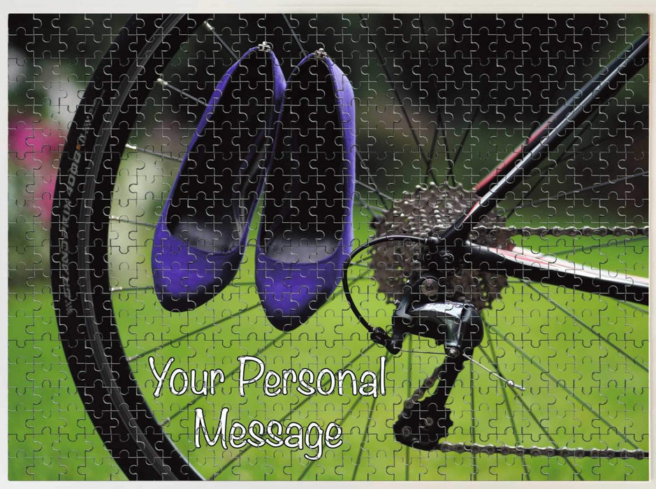 A jigsaw seen from the top, the jigsaw having an image of a pair of purple high heel shoes hung on the rear wheel of a road bike, along with a personal message