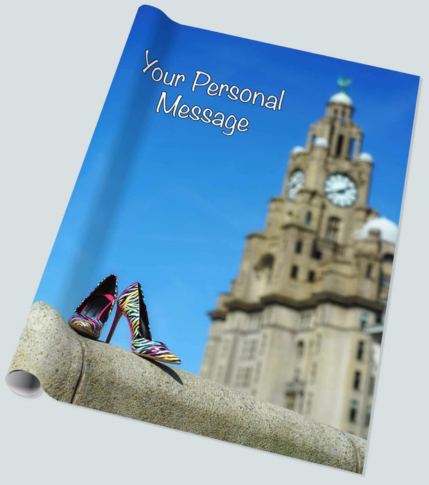 A roll of wrapping paper showing an image of the famous liverpool cunard liver building with a pair of high heel shoes on a wall in the foreground along with a personal message
