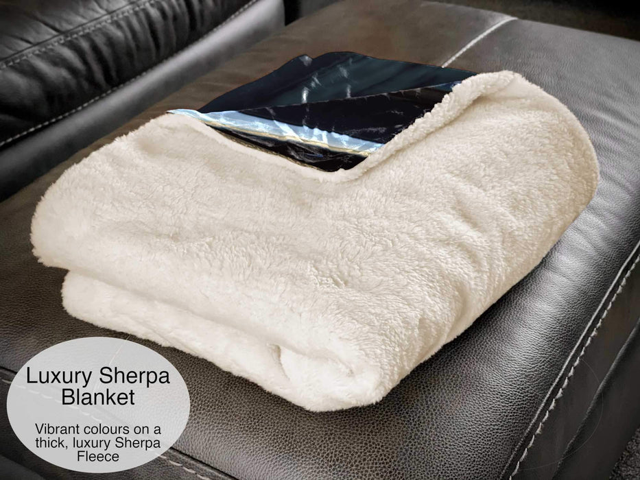 A white sherpa fleece blanket folded and sat on a couch