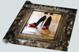 A roll of wrapping paper showing a mirror, the mirror surrounded by a brass mount, an in the mirror is a reflection of a pair of orange high heel shoes along with a personal message