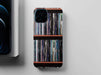 overhead view of a mobile phone case with images of vinyl records stacked along a shelf on the case, sat adjacent to a partially hidden iphone and iphone box