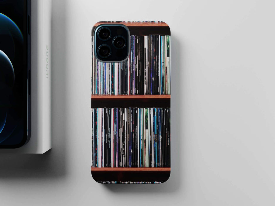overhead view of a mobile phone case with images of vinyl records stacked along a shelf on the case, sat adjacent to a partially hidden iphone and iphone box