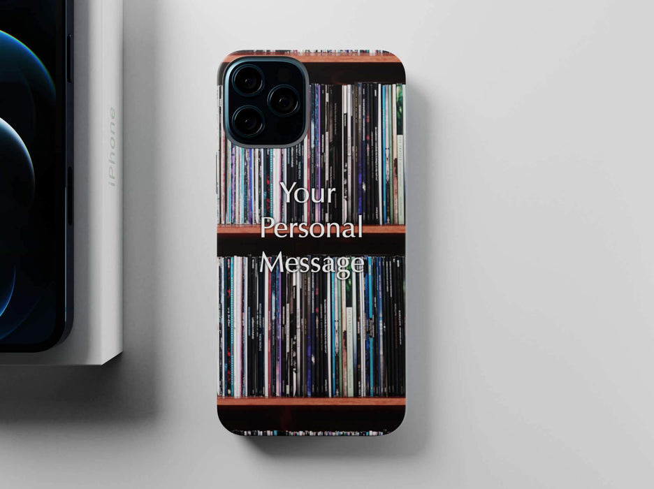 overhead view of a mobile phone case with images of vinyl records stacked along a shelf on the case along with a personal message, sat adjacent to a partially hidden iphone and iphone box